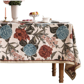 Cream tablecloth with large burgundy and teal flowers and dark leafy stems.