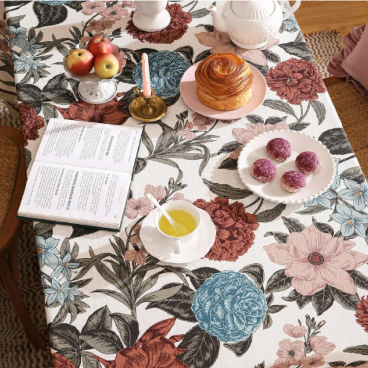 Overhead view of a burgundy and teal floral tablecloth beneath tea and pastries.