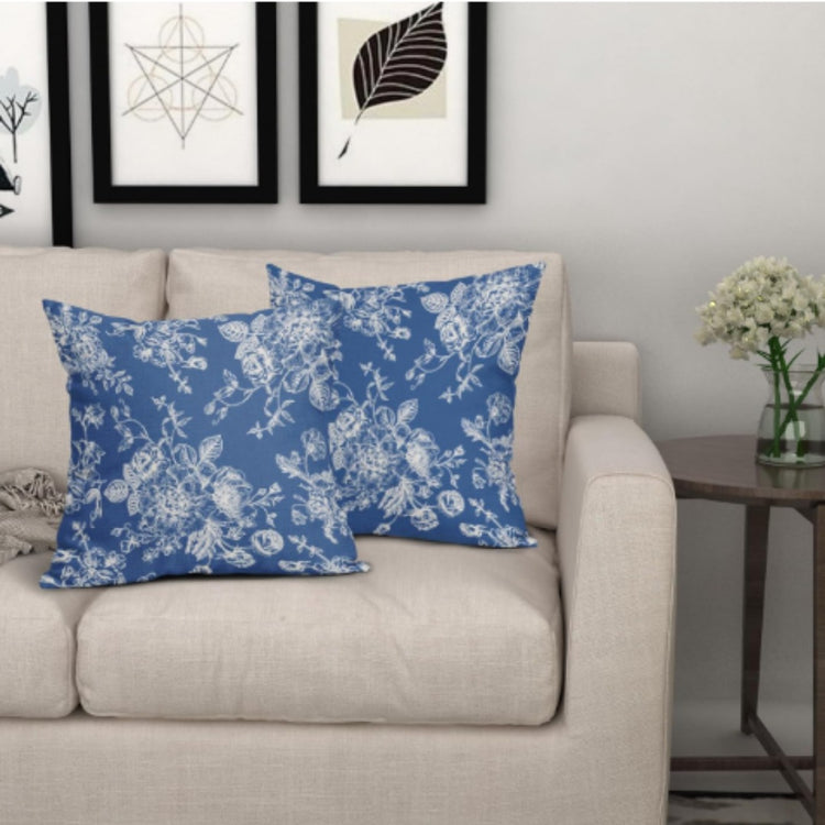 Two blue cushion covers with delicate white floral patterns on a beige sofa.