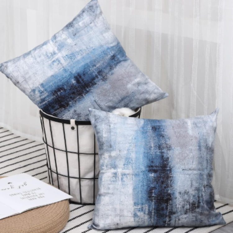 Two cushion covers with a distressed blue and grey horizontal pattern on a wire chair.