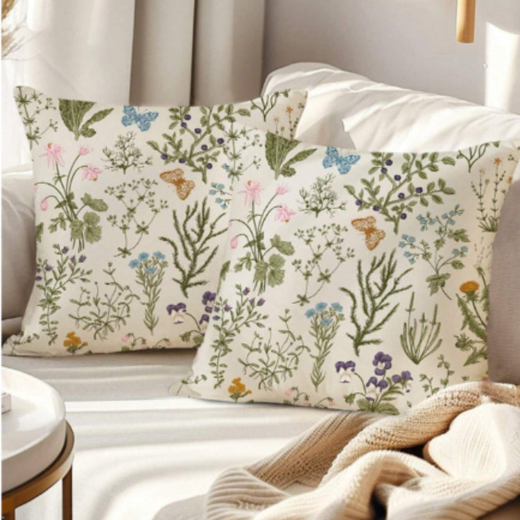Two cream cushion covers with delicate green stems and small colourful wildflowers on a sofa.
