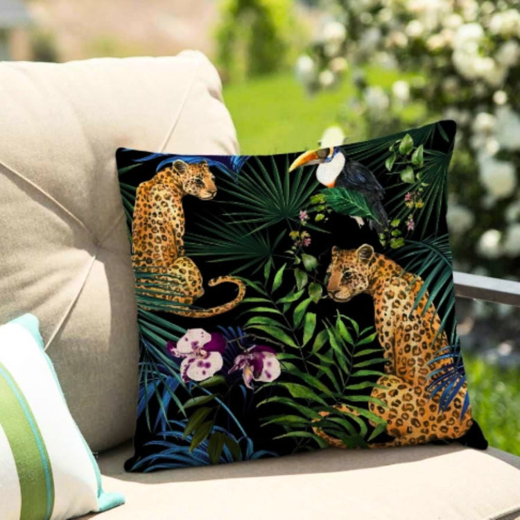 Black cushion cover with spotted big cats and tropical flowers on an outdoor seat.