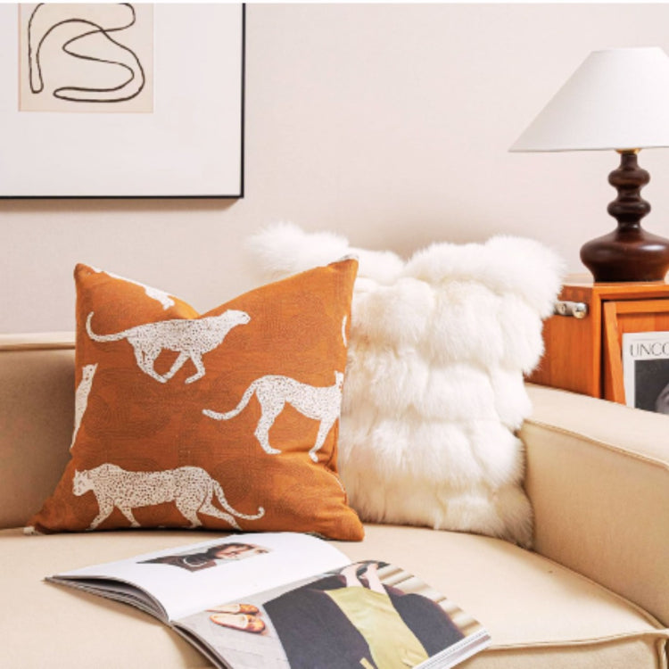 Rust cushion cover with cream leopard silhouettes beside a white textured cushion.