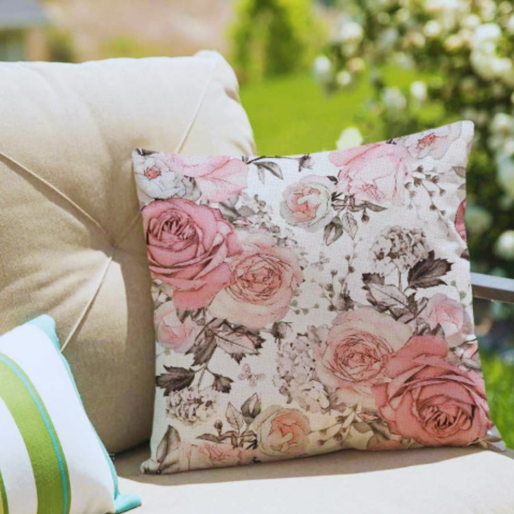 Cream cushion cover with pink roses and grey botanical details on an outdoor seat.