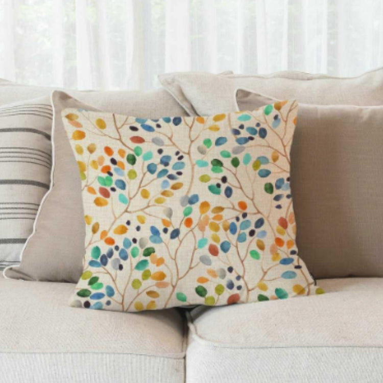 Cream cushion cover with small blue, green and yellow leaves on a sofa.
