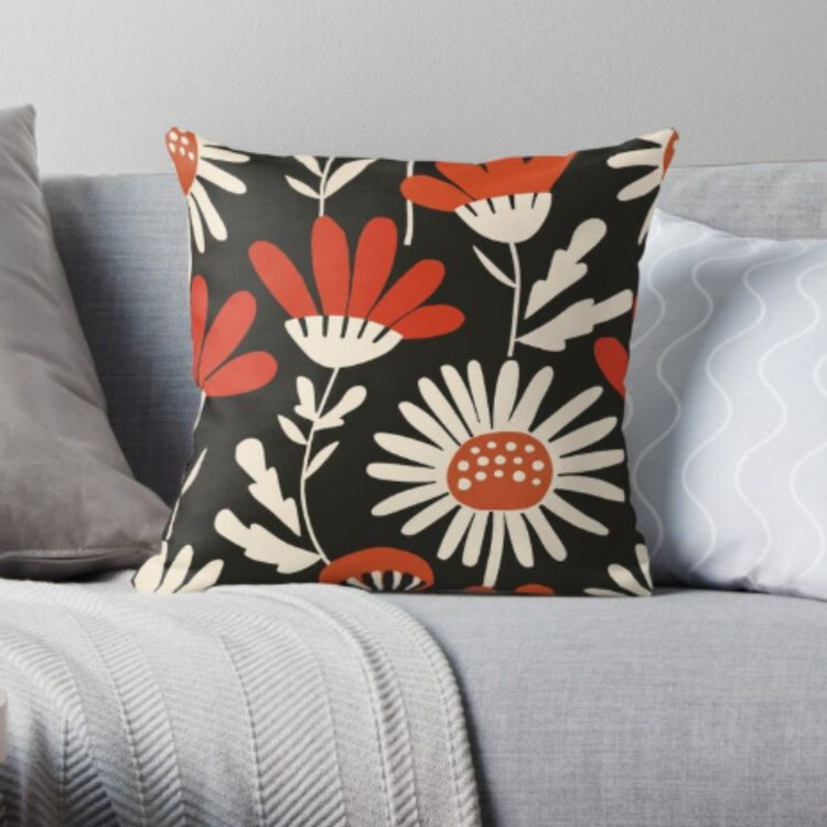 Black cushion cover with large red and cream flowers and pale leaves.