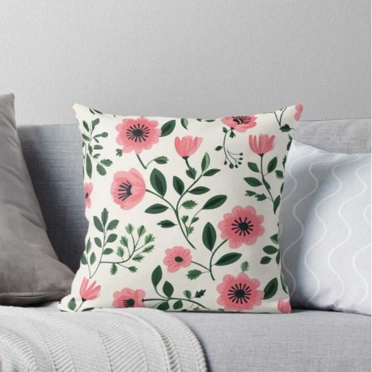 Cream cushion cover with bright pink flowers and dark green leaves.