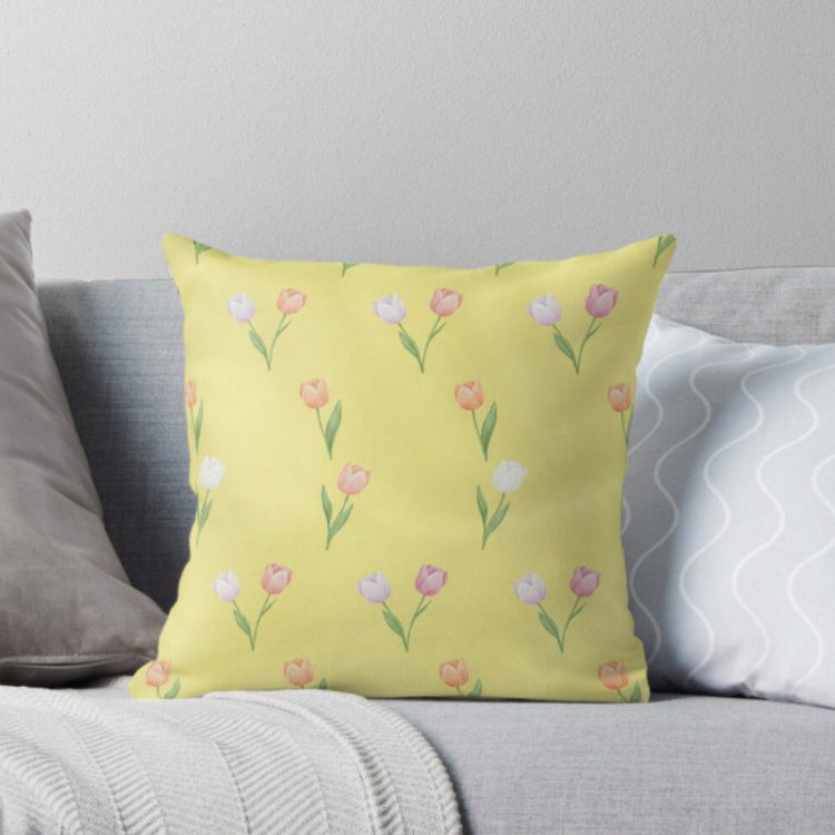 Pale yellow cushion cover with delicate pink tulips and green stems.