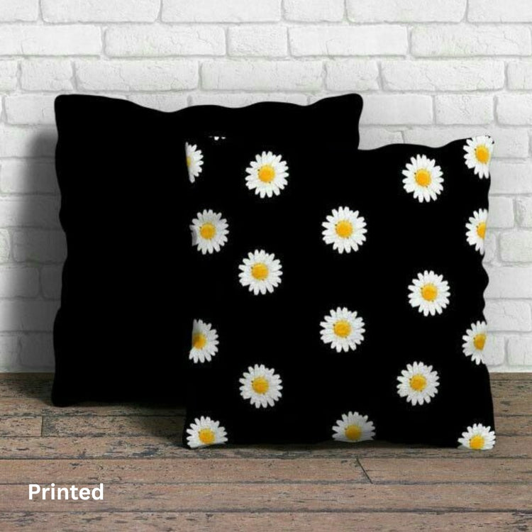 Close view of black cushion covers with small white daisies and yellow centres.