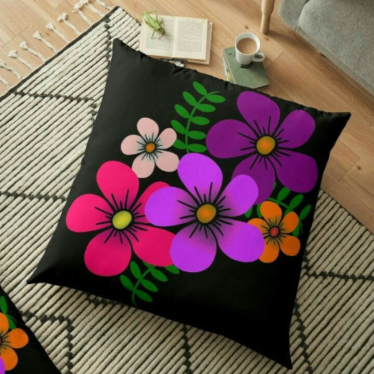 Black cushion cover with large pink and purple flowers and bright green leaves.