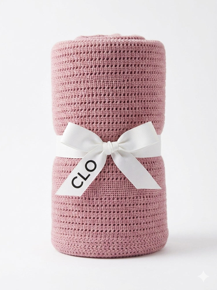 Rolled dusty pink cellular blanket standing upright and tied with a white CLO ribbon.
