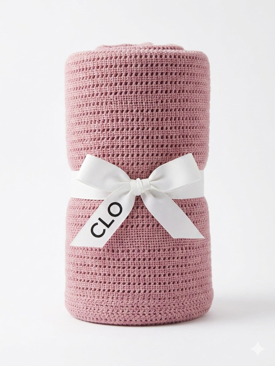 Rolled dusty pink cellular blanket standing upright and tied with a white CLO ribbon.