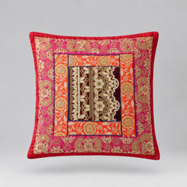 Red-bordered cushion cover with ornate pink and gold coloured floral bands and a dark patterned centre.