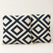 Two cream cushion covers with bold navy interlocking diamond patterns on a sofa.