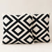 Two cream cushion covers with bold black interlocking diamond patterns on a sofa.