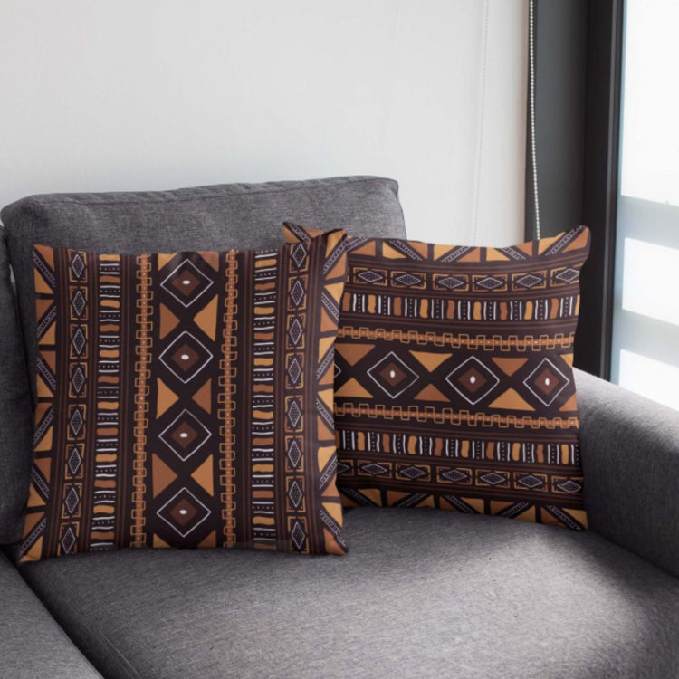 Two dark brown cushion covers with ochre diamonds and narrow geometric borders on a chair.