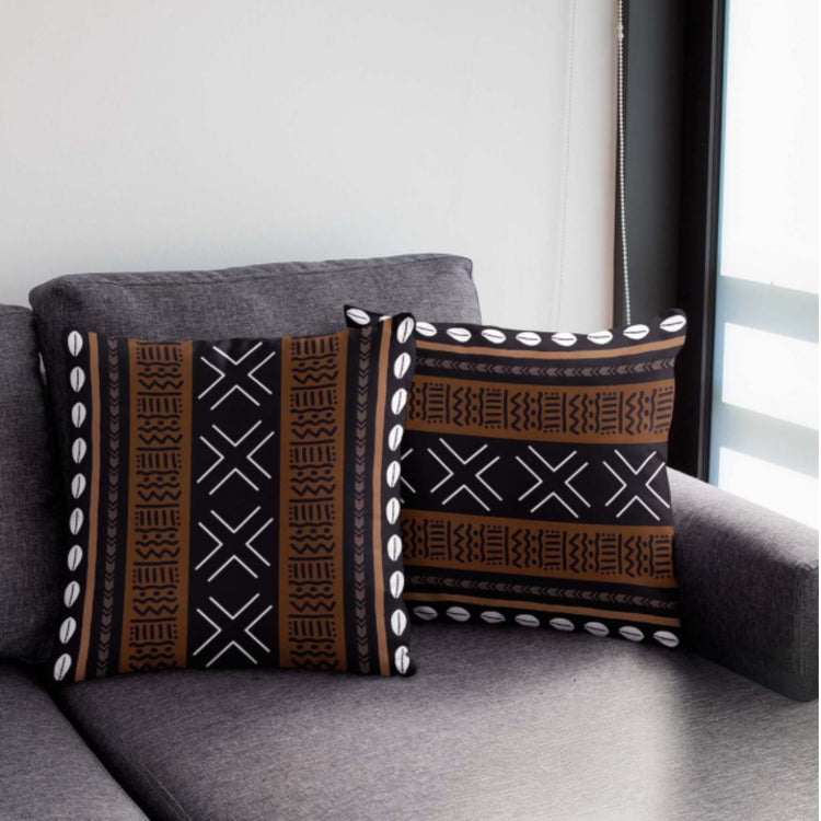 Two brown and black cushion covers with geometric bands and white dot borders on a chair.