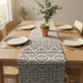 Cream table runner with blue and rust geometric patterns on a wooden dining table.
