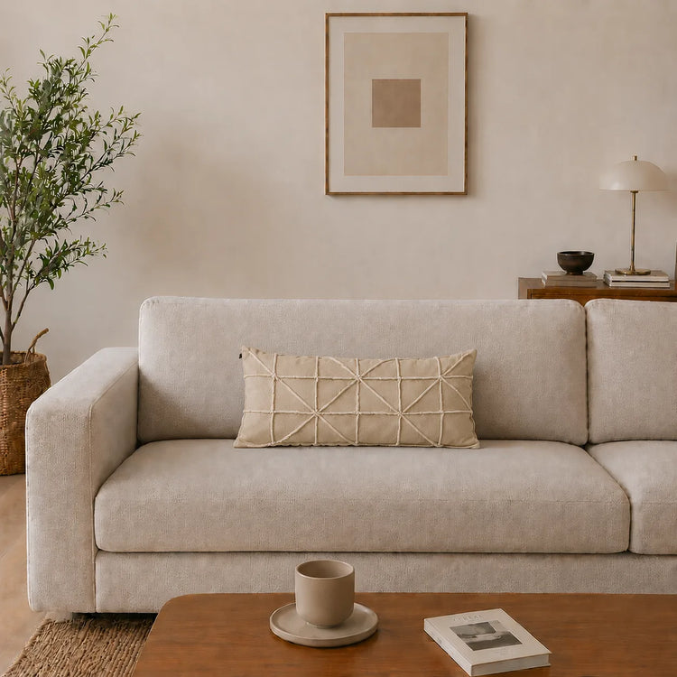 Rectangular cream filled cushion with intersecting geometric stitching on a cream sofa.