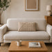 Rectangular cream filled cushion with angular stitched lines on a cream sofa.