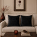 Two black cushion covers with fine horizontal stitched lines on a beige sofa.