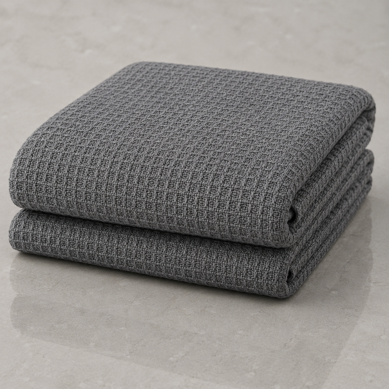 Folded grey waffle-weave blanket on a neutral surface.