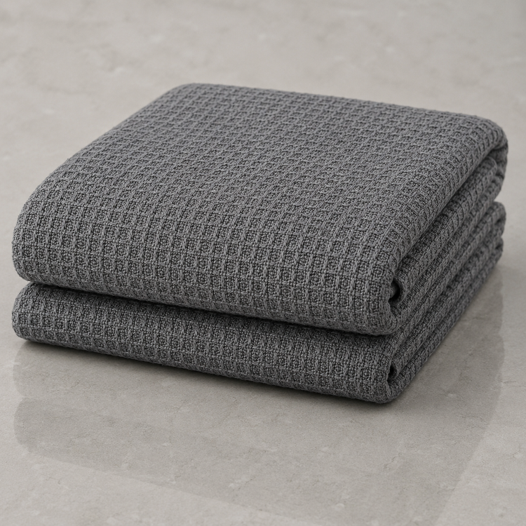 Folded grey waffle-weave blanket on a neutral surface.