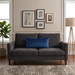 Rectangular blue filled cushion with diamond stitching on a dark grey sofa.