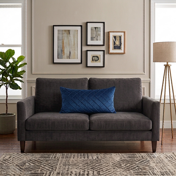 Rectangular blue filled cushion with diamond stitching on a dark grey sofa.