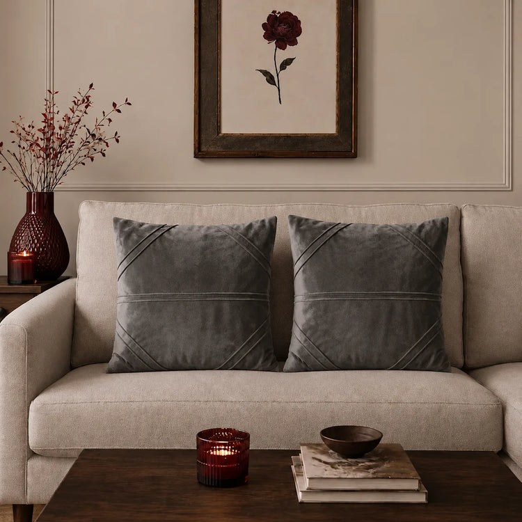 Two dark grey cushion covers with fine horizontal stitched lines on a beige sofa.