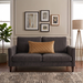 Rectangular tan filled cushion with diamond stitching on a dark grey sofa.