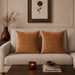Two tan cushion covers with fine horizontal stitched lines on a beige sofa.