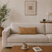 Rectangular tan filled cushion with intersecting geometric stitching on a cream sofa.