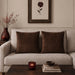 Two brown cushion covers with fine horizontal stitched lines on a beige sofa.