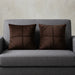 Two dark brown cushion covers with geometric panel stitching on a grey sofa.