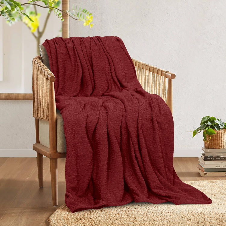 Burgundy cotton thermal blanket draped over a wooden armchair.