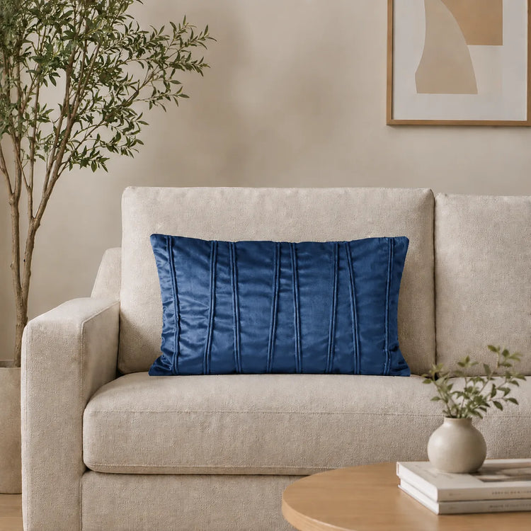 Rectangular blue filled cushion with vertical stitched texture on a cream sofa.
