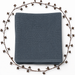 Folded dark grey waffle-textured blanket with a plain border, framed by decorative dried branches.