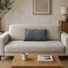 Rectangular dark grey filled cushion with angular stitched lines on a cream sofa.