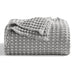 Folded grey waffle-weave blanket on a white background.