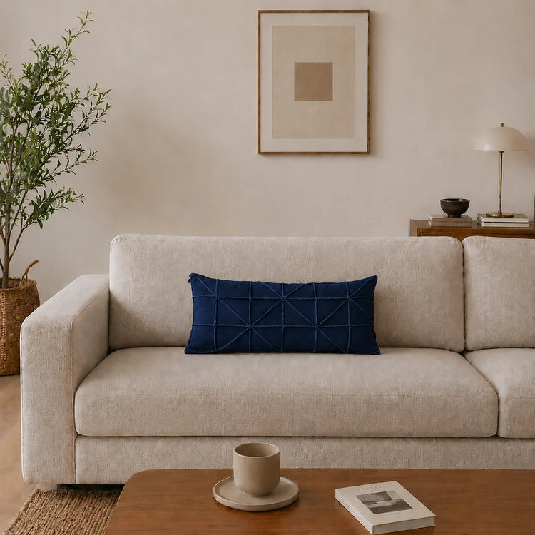 Rectangular navy filled cushion with intersecting geometric stitching on a cream sofa.