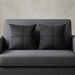 Two charcoal grey cushion covers with geometric panel stitching on a grey sofa.