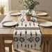 Cream table runner with blue and rust geometric motifs on a wooden dining table.