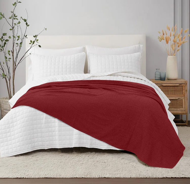 Burgundy cotton thermal blanket spread across a bed.