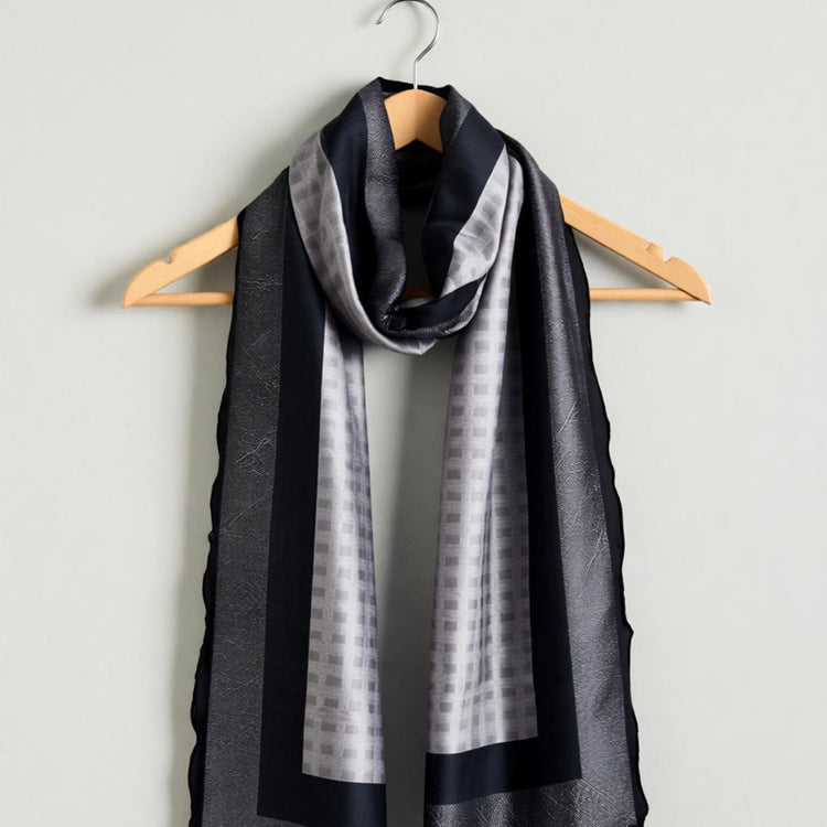 Grey and black scarf draped on a wooden hanger.