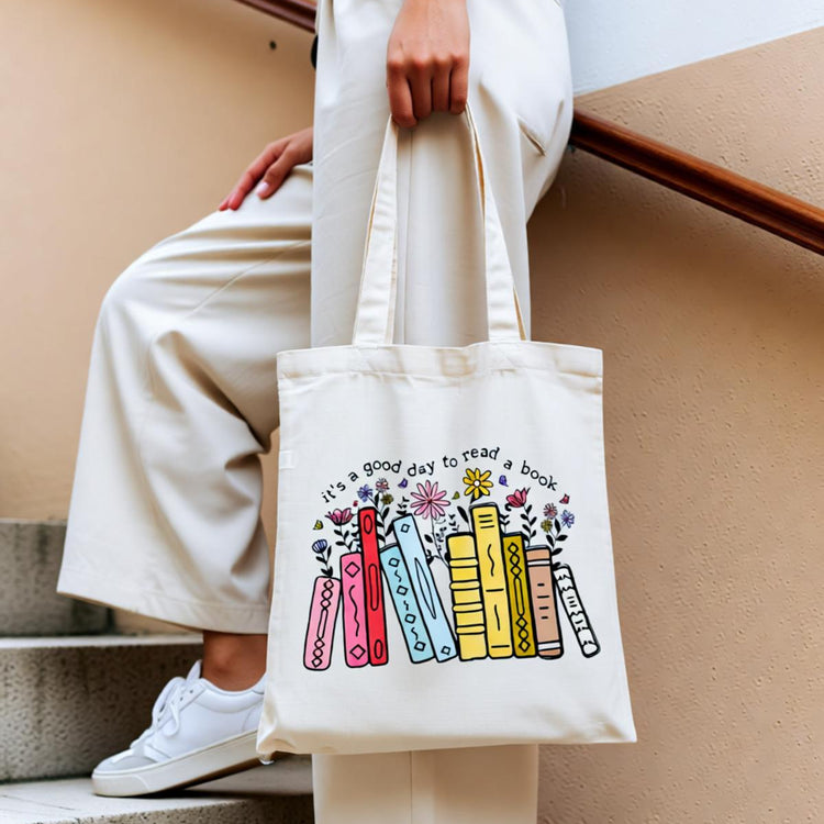 Cream tote bag with colourful books and small flowers.
