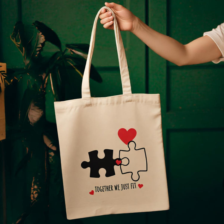 Cream tote bag with interlocking puzzle pieces and small red hearts.