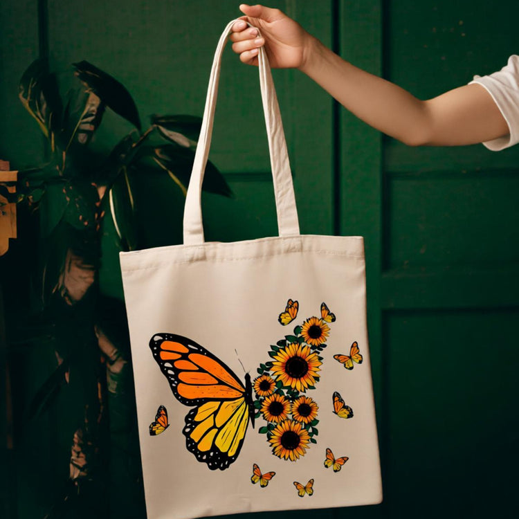 Cream tote bag with a yellow butterfly and sunflower illustration.