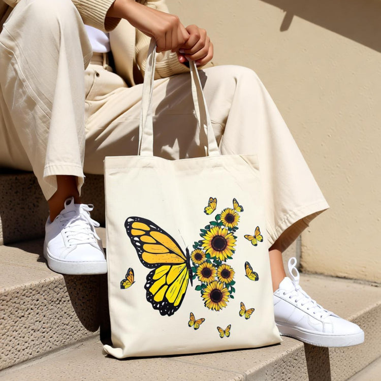 Cream tote bag with a yellow butterfly and sunflower illustration.