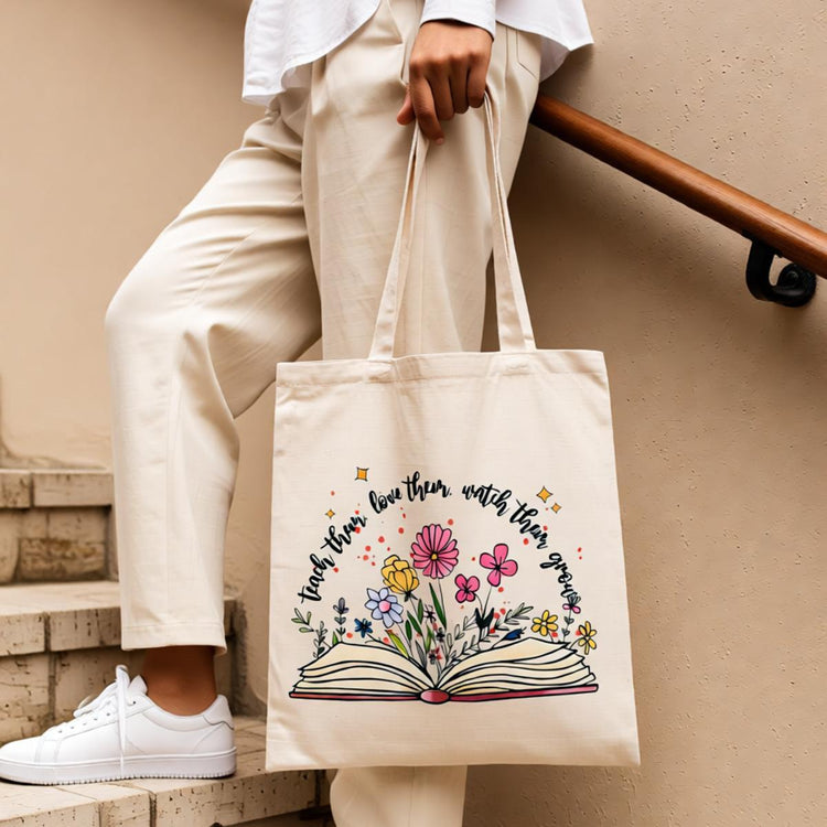 Cream tote bag with an open book and colourful flowers.
